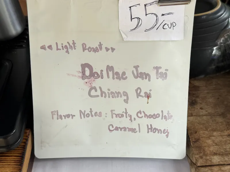 Hand-lettered coffee bag reading Doi Mae Jan Tai, Chiang Rai, light roast, with a handwritten 55 baht per cup sign